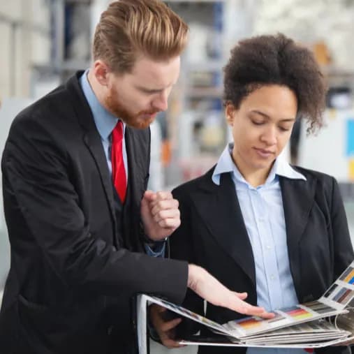 Two people comparing printed reference materials