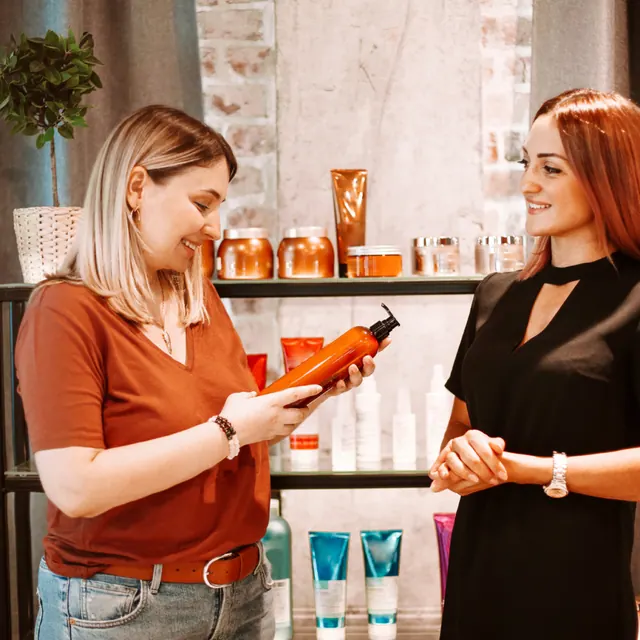 Beauty-Beraterin zeigt einer Kundin ein Hautpflegeprodukt
