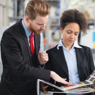 Two people comparing printed reference materials