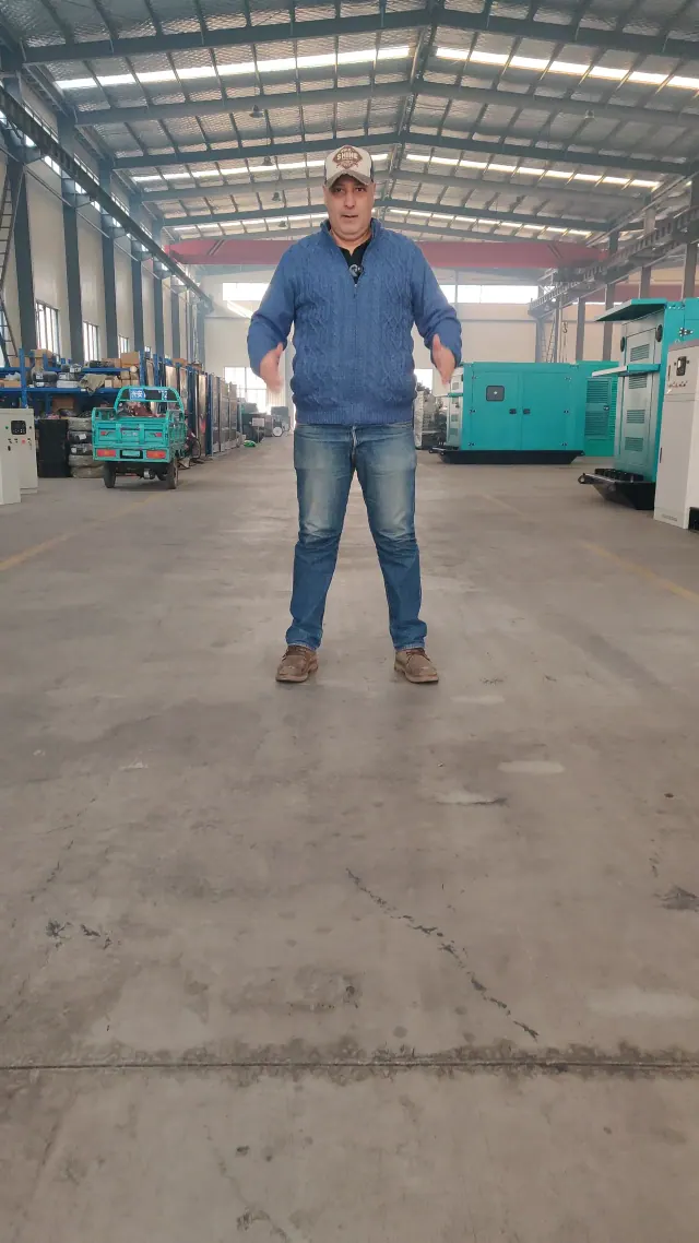 A person stands beside generator production equipment during a factory visit.
