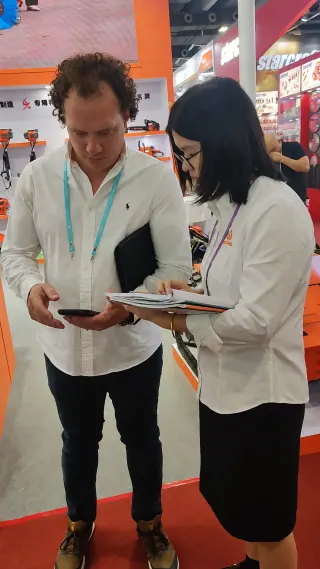 两人在2024年展会的供应商展位前，一起查看产品目录。
